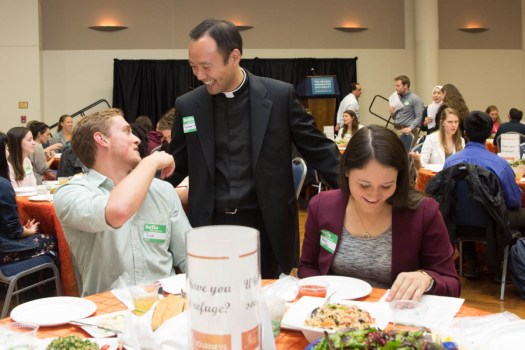 Adam Park, chaplain of George Washington the Newman Center, greets students at the university's Interfaith Journeys Dinner.